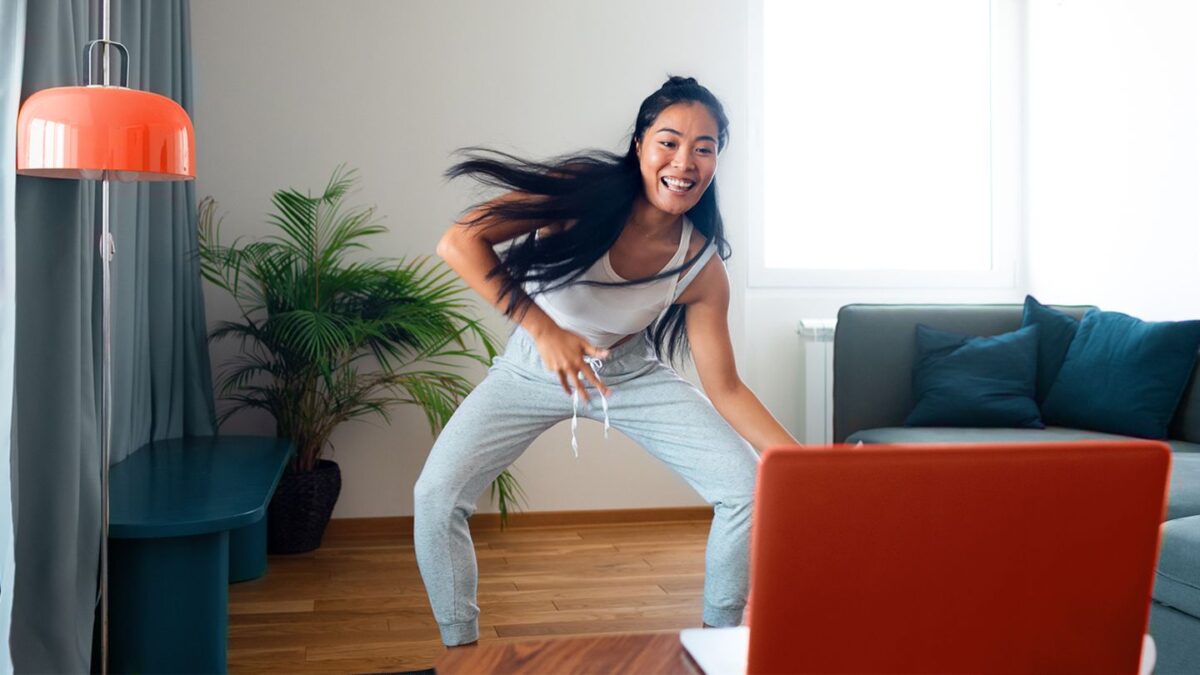woman dancing to kpop songs in front of a laptop